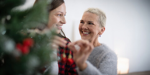 Fototapeta premium Family winter holiday and concept happy senior woman with adult daughter decorate christmas tree at home