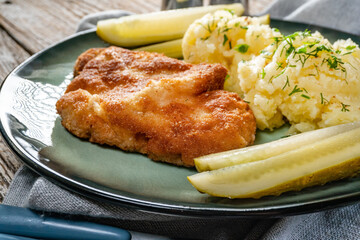 Pork chop served with mashed potatoes and pickled cucumber.
