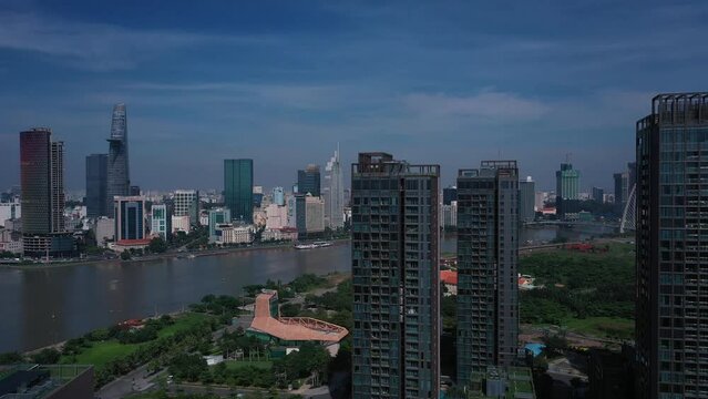 Aerial Vietnam, Ho Chi Minh City  iconic buildings of Skyline on sunny clear day featuring architecture, and Saigon River. Camera moves CCW around high-rise towers revealing view.