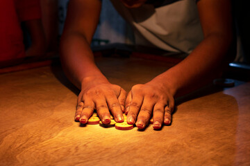 A young boy playing carom board under light, selective focus. - obrazy, fototapety, plakaty