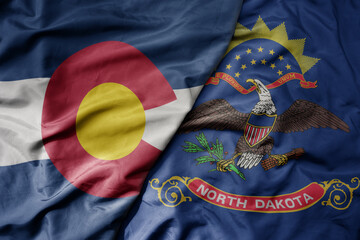 Fototapeta na wymiar big waving colorful national flag of north dakota state and flag of colorado state .