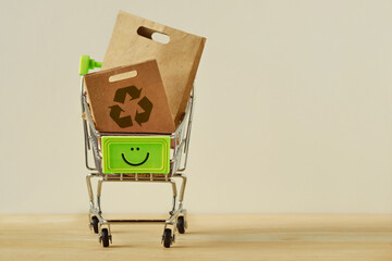 Shopping cart with happy face and paper shopping bags with recycle symbol - Ecology and recycling concept
