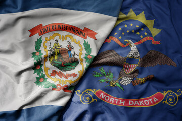 big waving colorful national flag of north dakota state and flag of west virginia state .