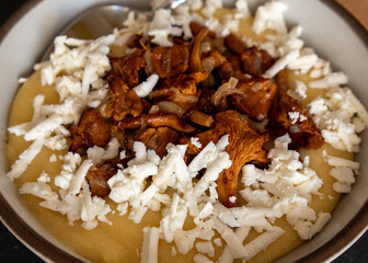 Tasty banosh served with brynza and mushrooms in bowl on table, top view. Traditional Ukrainian dish