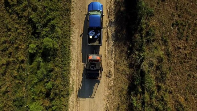 Aerial Top Upward Shot Of Pickup Truck With Tractor Part Moving On Road Amidst Meadow Landscapes During Sunny Day - Bayou, Louisiana