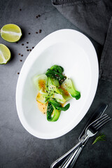 bok choy cabbage with sesame seeds and sauce in a white plate, top view