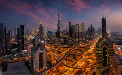 Elevated, panoramic view of the illuminated skyline of Dubai City center and busy Sheikh Zayed road intersection, United Arab Emirates, during evening time