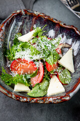 salad with herbs, tomatoes, grated cheese, sesame seeds and pieces of cheese, top view