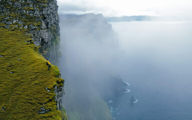 Hiker standing on edge of famous rock cliff. Concept: Adventure, Explore, Hike, Lifestyle. Faroe...