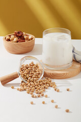 A lot of soybeans displayed on white surface with a cup of milk and wooden bowl of many nuts.Research suggests that nuts and beans may reduce inflammation