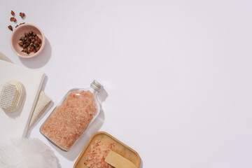 Bath essentials showcased on a white backdrop adorned with blush pink salt. Unwind with pure ingredients. Ideal for promotional and product presentation. Artistic setting.
