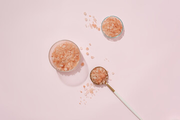 Himalayan pink salt is displayed on props against a pastel pink background. Himalayan salt contains more than 80 minerals and elements, including potassium, iron and calcium.