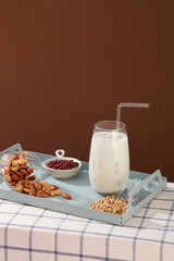 Over brown background, a pastel tray featured many types of nuts and beans with a fresh milk cup. Nuts are a convenient treat that can be enjoyed on all kinds of diets