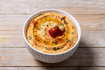 Roasted red pepper hummus in white bowl on wooden table