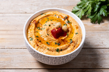 Roasted red pepper hummus in white bowl on wooden table