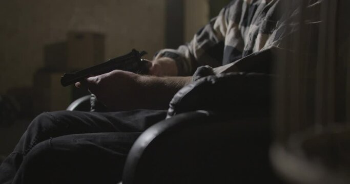 Male hands holding gun in dark warehouse interior, close up shot