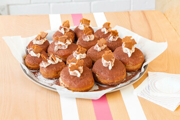 Indulgent Tiramisu Doughnut Held by woman's hand Indoors at a bakery.