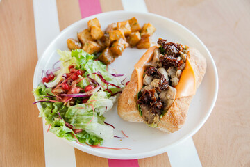Chicken open faced sandwich in ciabatta bread served with veggies on the side.
