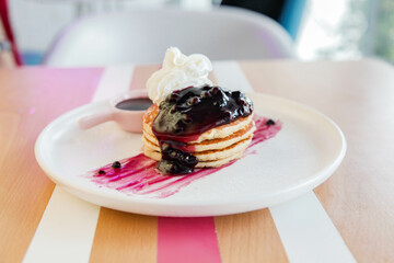Raspberry pancake with whipped cream served in a cafe environment.