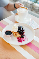 Raspberry pancake with whipped cream served in a cafe environment.