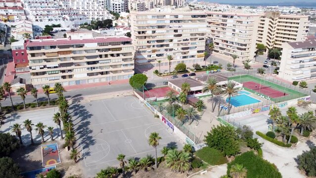 Aerial drone video at Cabo Cervera, Torrevieja showing park, swimming pool and tennis court