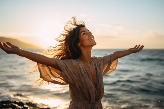 An image of a young, pretty woman standing at the water's edge on a sun-kissed beach, her arms outstretched as she embraces the liberating feeling of the ocean breeze