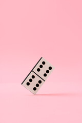 Domino piece on pink background close up