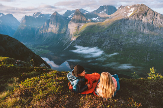 Friends couple in sleeping bags on a Norway mountain bivouac, man and woman hiking with camping travel gear, romantic outdoor vacations active healthy lifestyle adventurous tour