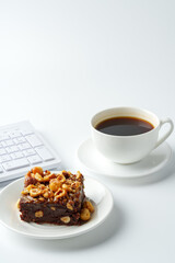 Piece of brownie cake with hazelnuts on white background
