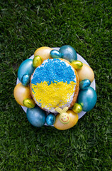 Fototapeta na wymiar chicken eggs painted yellow and blue around Easter cake decorated with colors of the Ukrainian flag