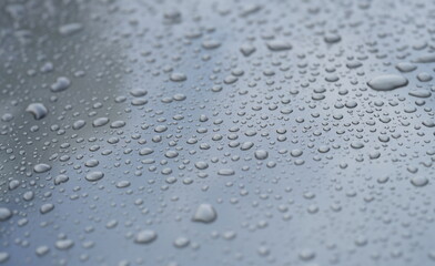 Raindrops on black hood of car. Rain on glass concept