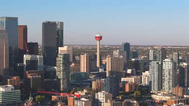 A aerial drone flies towards the Calgary tower on a beautiful sunny day with apartment buildings and condos in the foreground