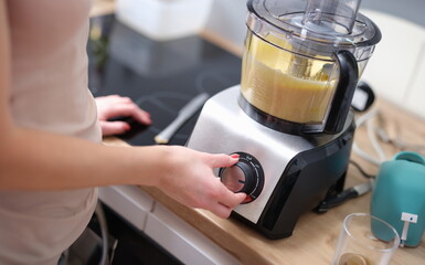 Woman adjusting speed of food processor. Pastry chef in kitchen turns on mixer or food processor...