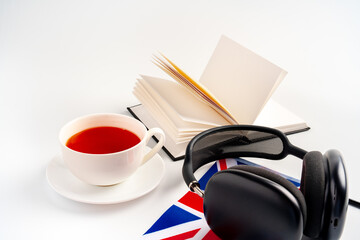Notepad with British flag and headphones on white background. English language audio courses educational concept