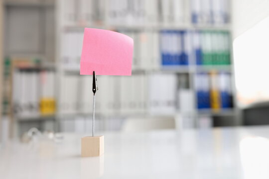 Pink blank note sticker on desk in office. Reminder day planning concept