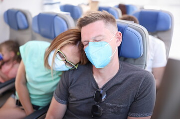 Fototapeta na wymiar Man and woman wearing protective respirators are flying in airplane. Safe flight during covid19 pandemic concept