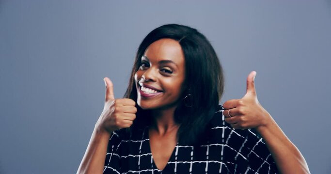Black woman, face and thumbs up in studio, like and positive review or feedback, agreement and opinion. Female person, emoji and icon or sign, portrait and dancing or smile, yes and gray background