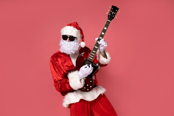 Fototapeta na wymiar Cheerful Santa Claus playing the guitar on a pink background.
