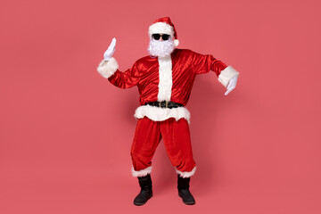 Fototapeta na wymiar Cheerful Santa Claus is dancing on a pink background.