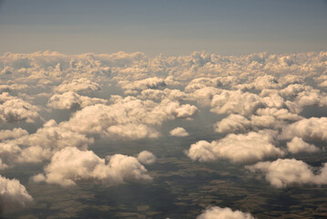 Aerial view of the thick and dramatic clouds from the airplane window in the sunset. Airplane above clouds. Flying, traveling and holidays concept. 
