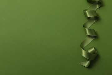 Green twisted ribbon on green background, space for text
