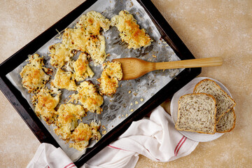 Cauliflower cheese in a baking dish on table with napkin and bread
