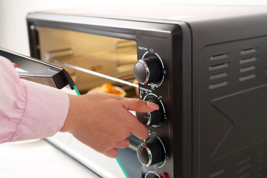 Woman's hands taking buscuit cupcakes out of mini oven