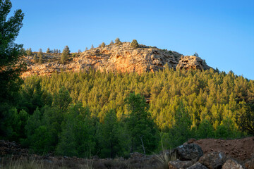 Side view of the mount called La Muela in Rincón de Ademuz, with rock strata and cave-shaped...