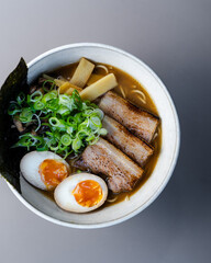 Miso Ramen Asian noodles soup with beef, egg and pak choi cabbage on black background, top view.