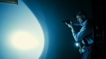 A male detective is aiming his gun while a female detective shines a flashlight into the darkness