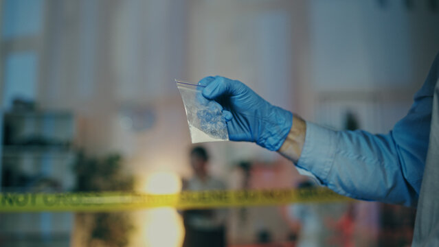 A detective is examining an illegal substance found at the crime scene during a police raid