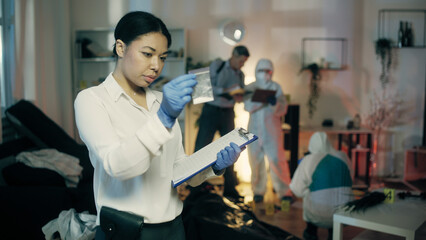 Obraz premium A black female detective is describing a bag with a substance in her report at the crime scene