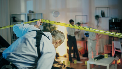 A detective is entering the crime scene to join his colleagues in the evidence collection process