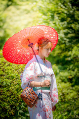 Portrait of a young woman wearing yukata summer kimono and holding Japanese traditional oil paper...